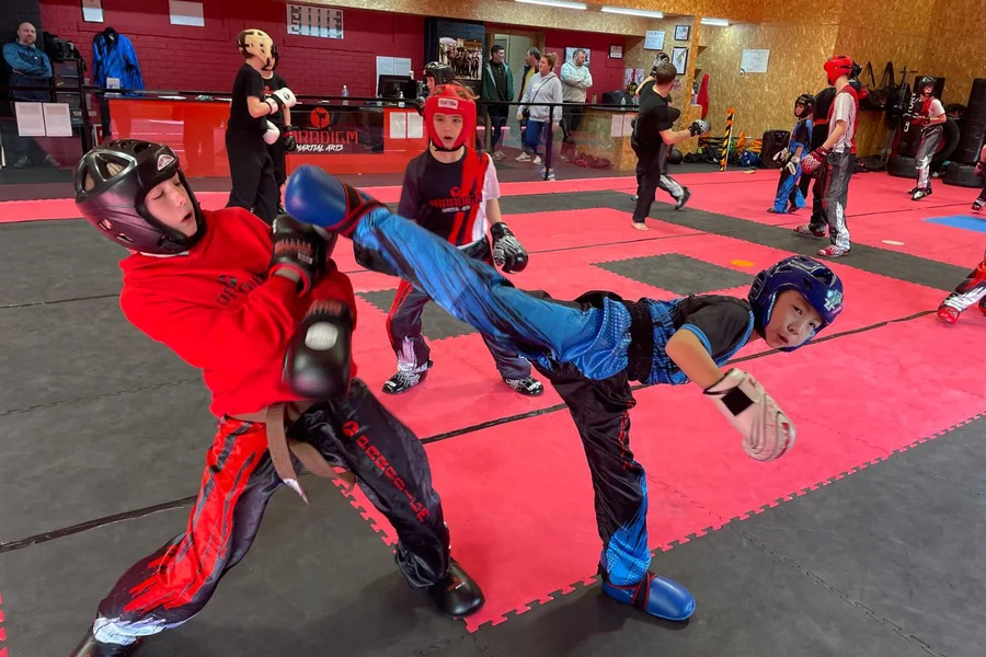 A Paradigm junior landing a jumping kick in a sparring drill